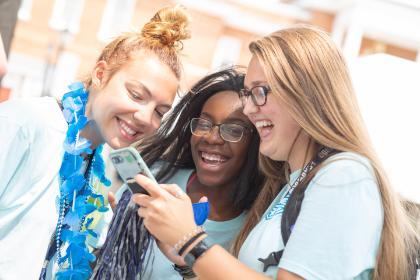 smiling Alumni look at phone 