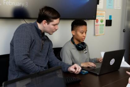 Two students sit and work on a laptop in the QR Center.