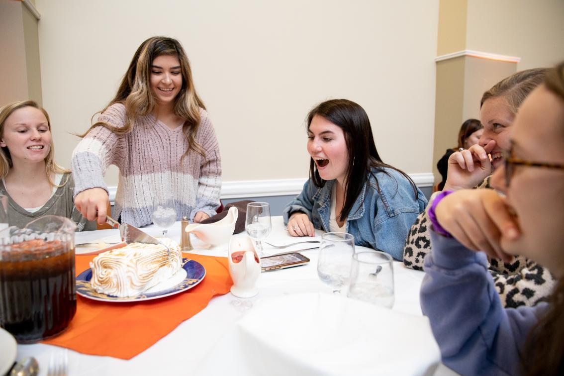 Students cuts the Baked Alaska while her fellow guests watch